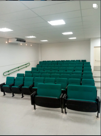 Sala de auditório com poltronas verdes em concha